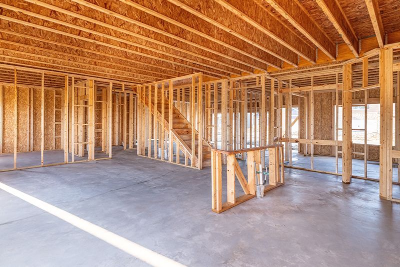A large empty room with wooden walls and a staircase in a house under construction.