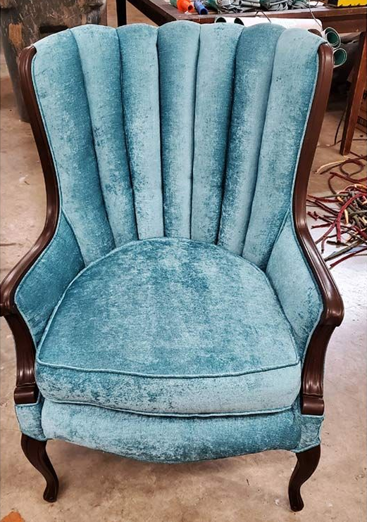 Teal velvet upholstered wingback chair with dark wood frame.