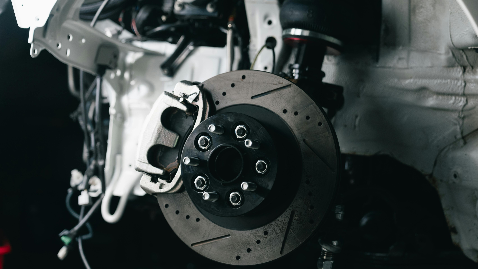 Close-up of a car brake rotor and caliper inside a wheel well, with metal components visible.