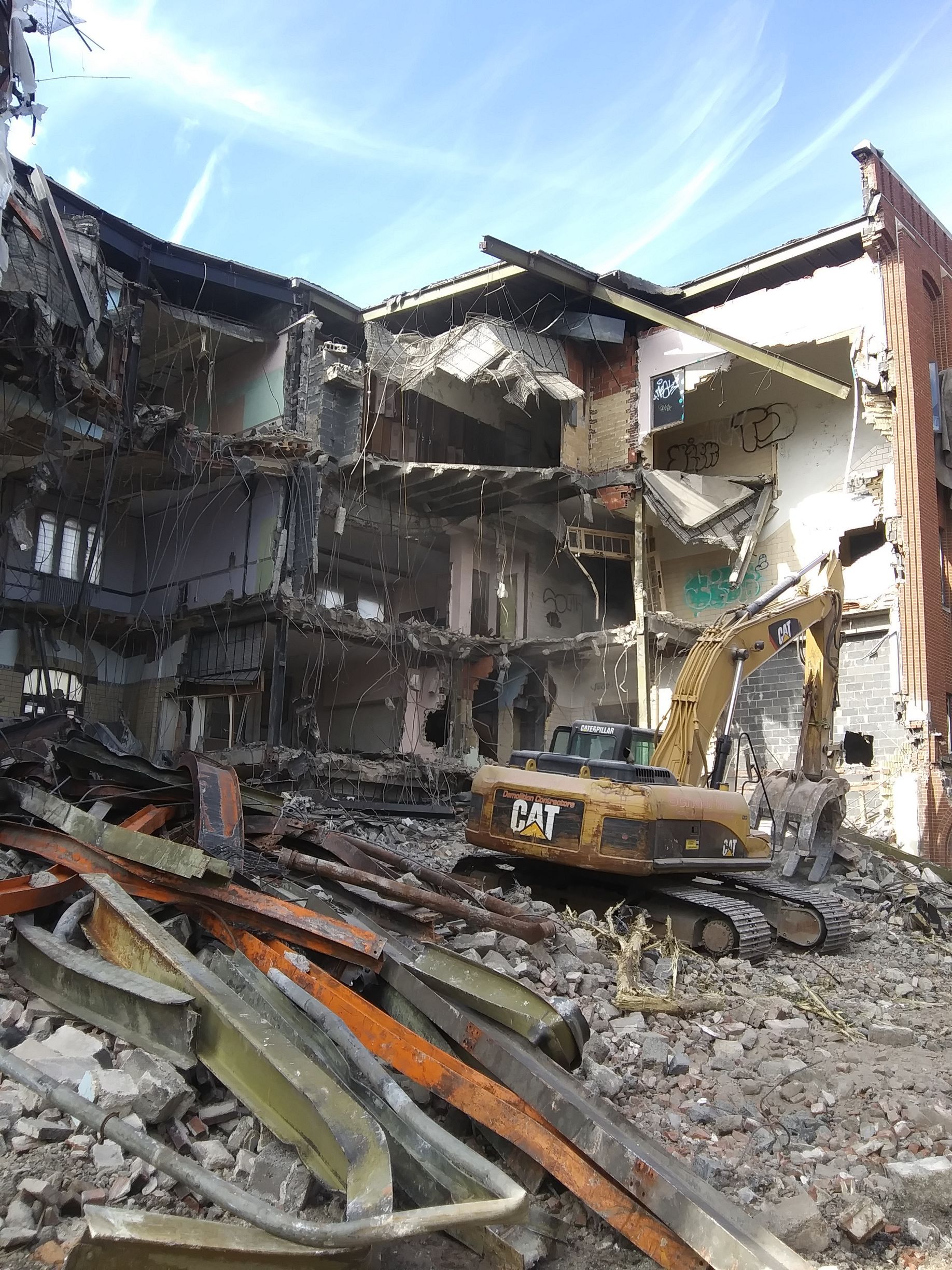 excavator in the middle of a large industrial building that is being demolished
