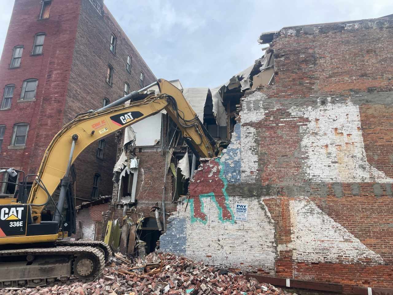 excavator tearing down a brick wall.