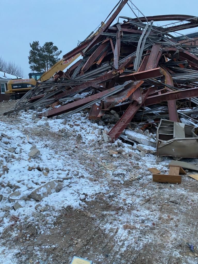 a pile of dirt, debris and steel beams after a demolition job