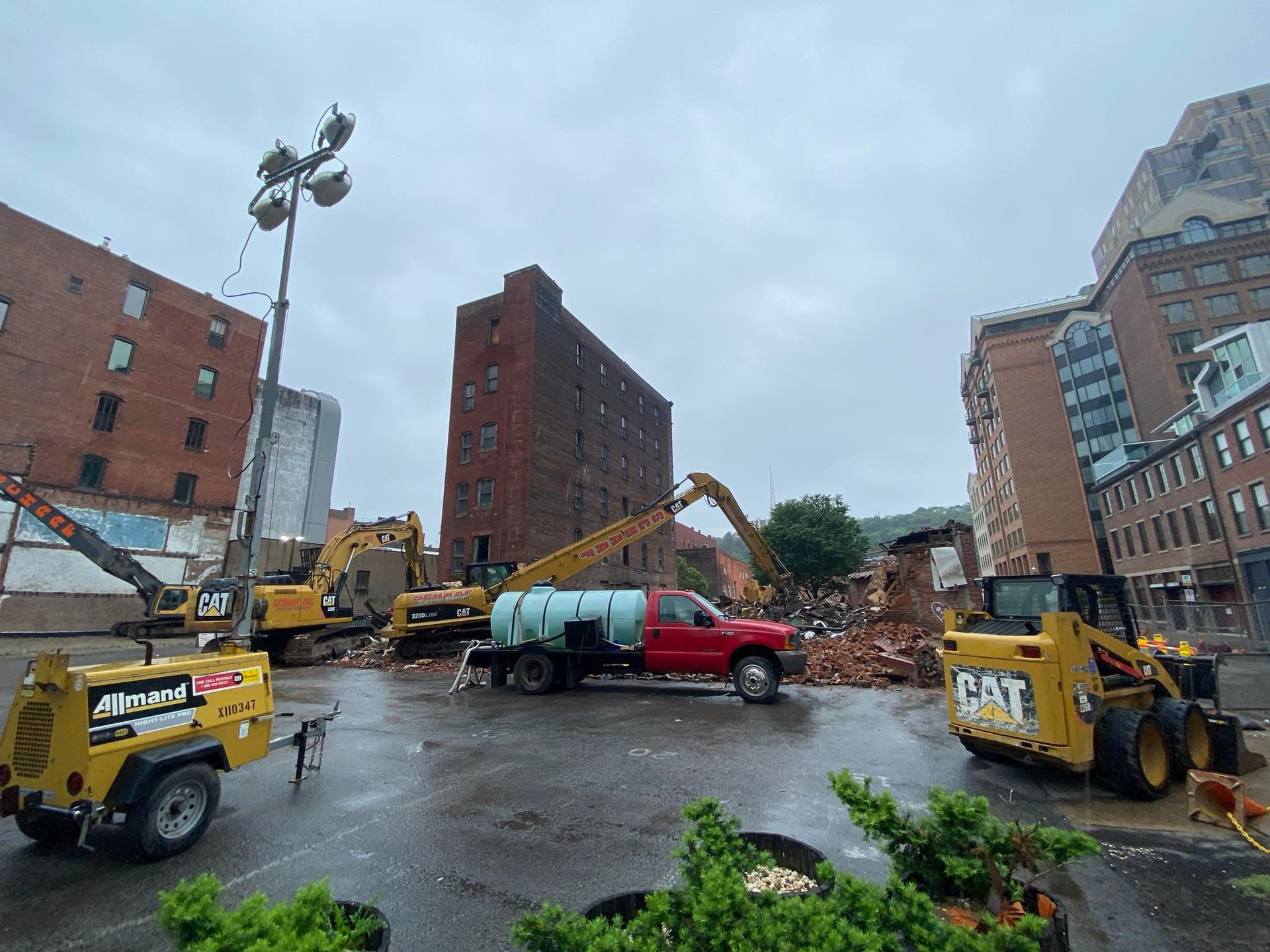 buildings being demolished, with alot of equipment including a red truck in the foreground