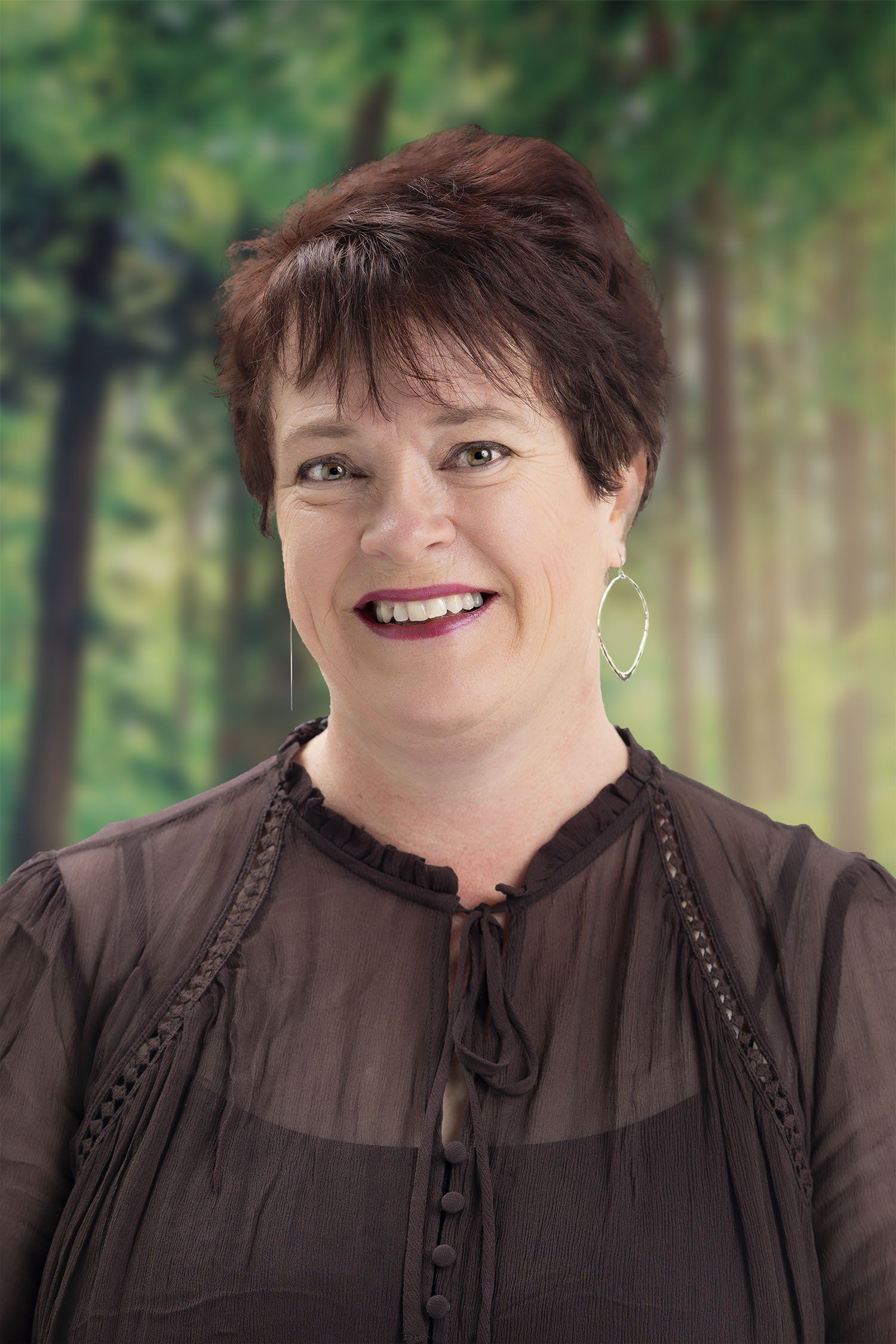 A woman wearing a black shirt and earrings is smiling for the camera.