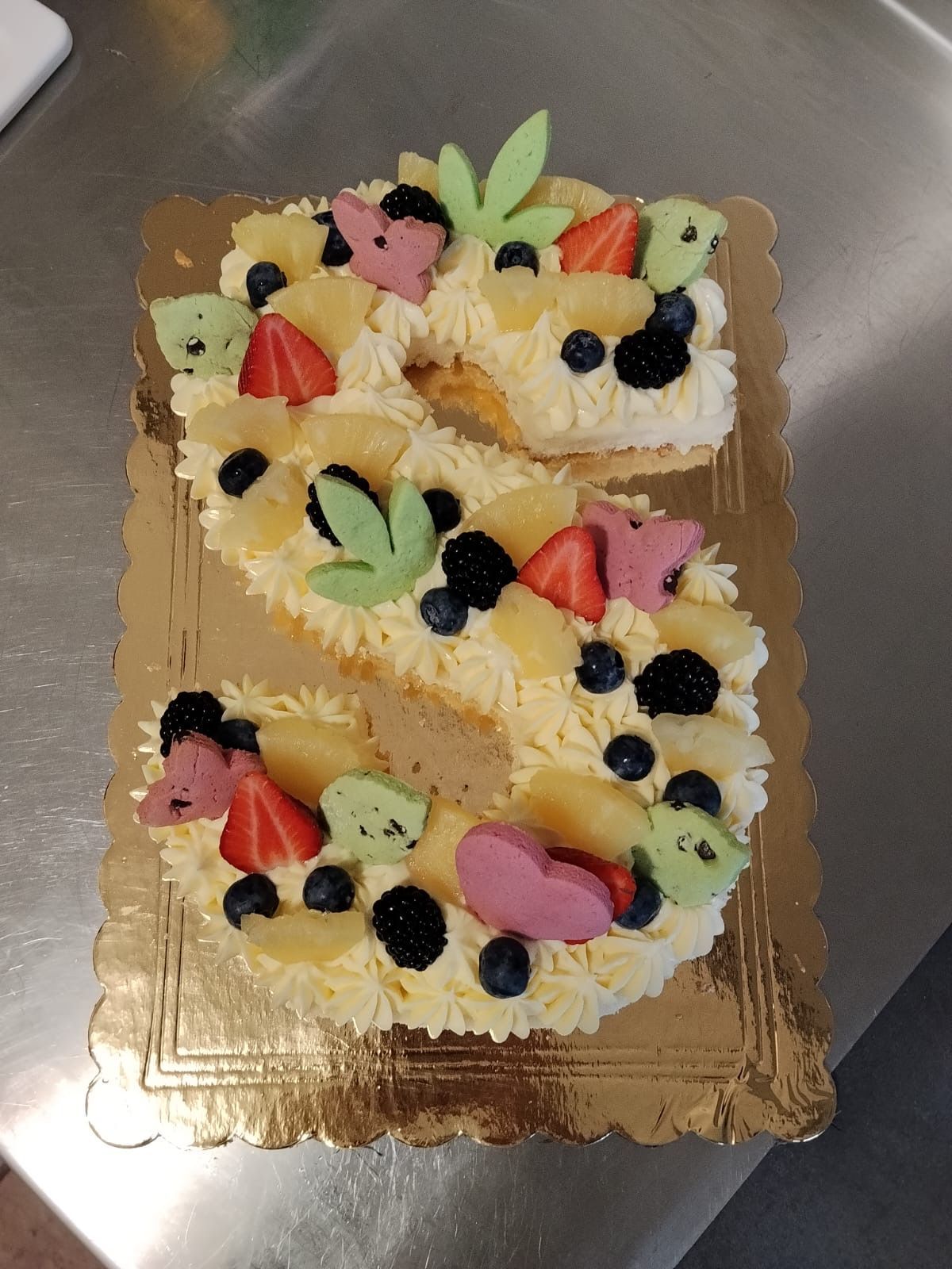 La lettera Z realizzata con panna montata e frutta su una base dorata per torte
