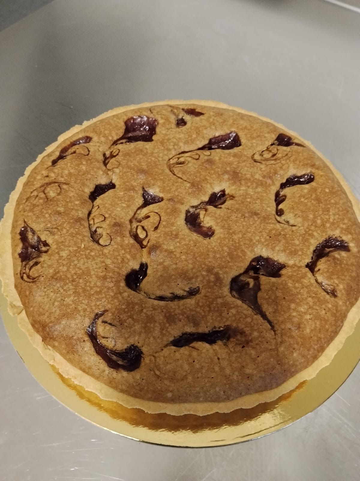 Torta rotonda al caramello decorata con riccioli di cioccolato, servita su un piatto bianco.