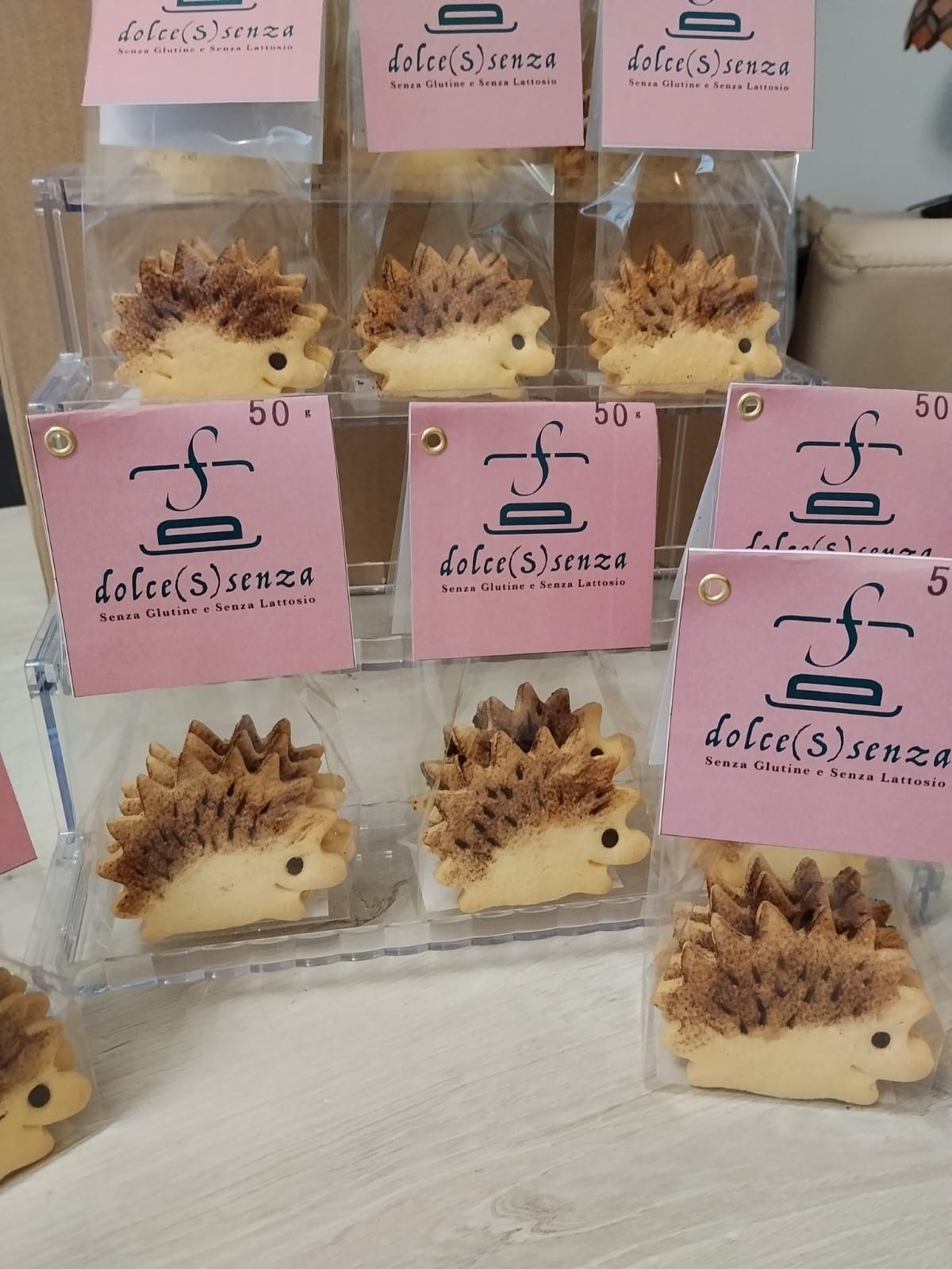 Esposizione di dolcetti artigianali a forma di riccio, in sacchetti trasparenti con etichette rosa, su un tavolo