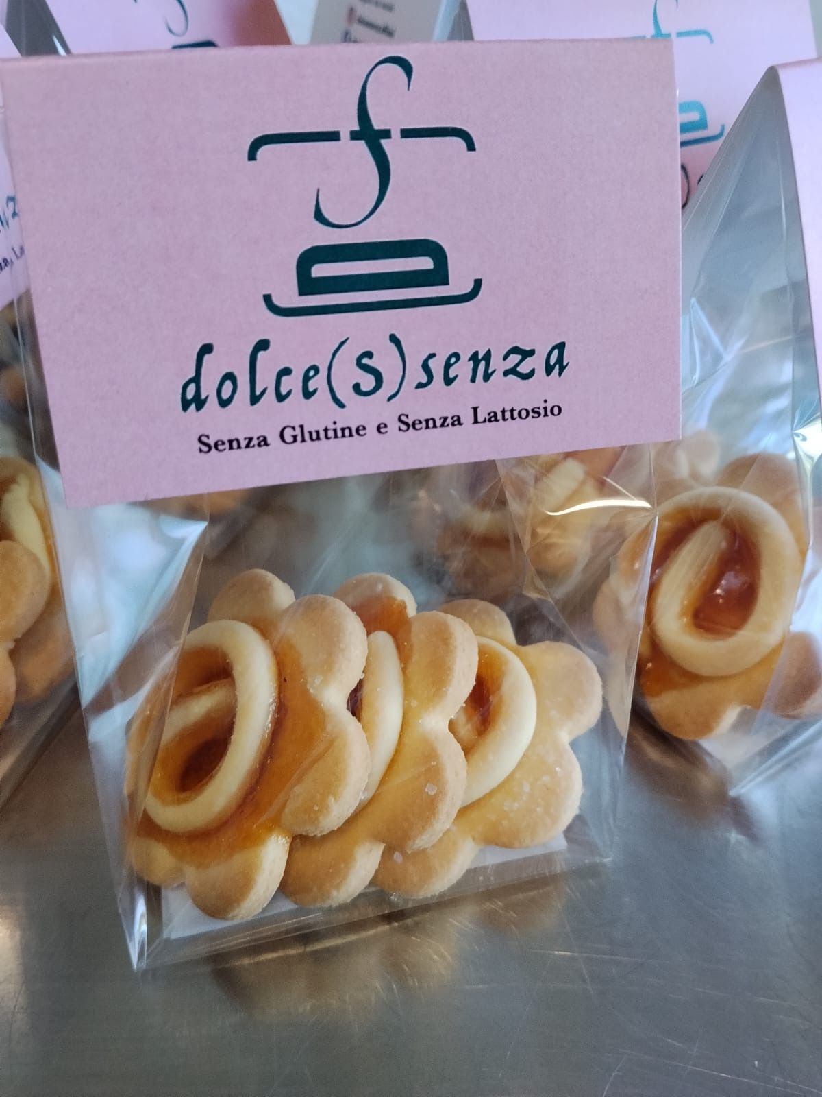 Biscotti a ciambella confezionati, con un cartello rosa senza glutine con la scritta “dolce(s)enza”