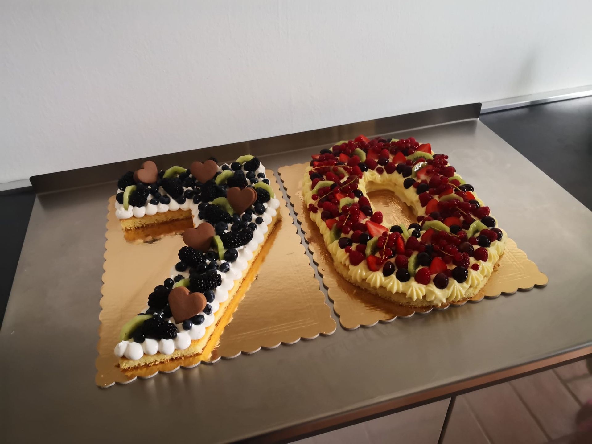 Due torte guarnite con frutta disposte a formare il numero 70 su un tavolo