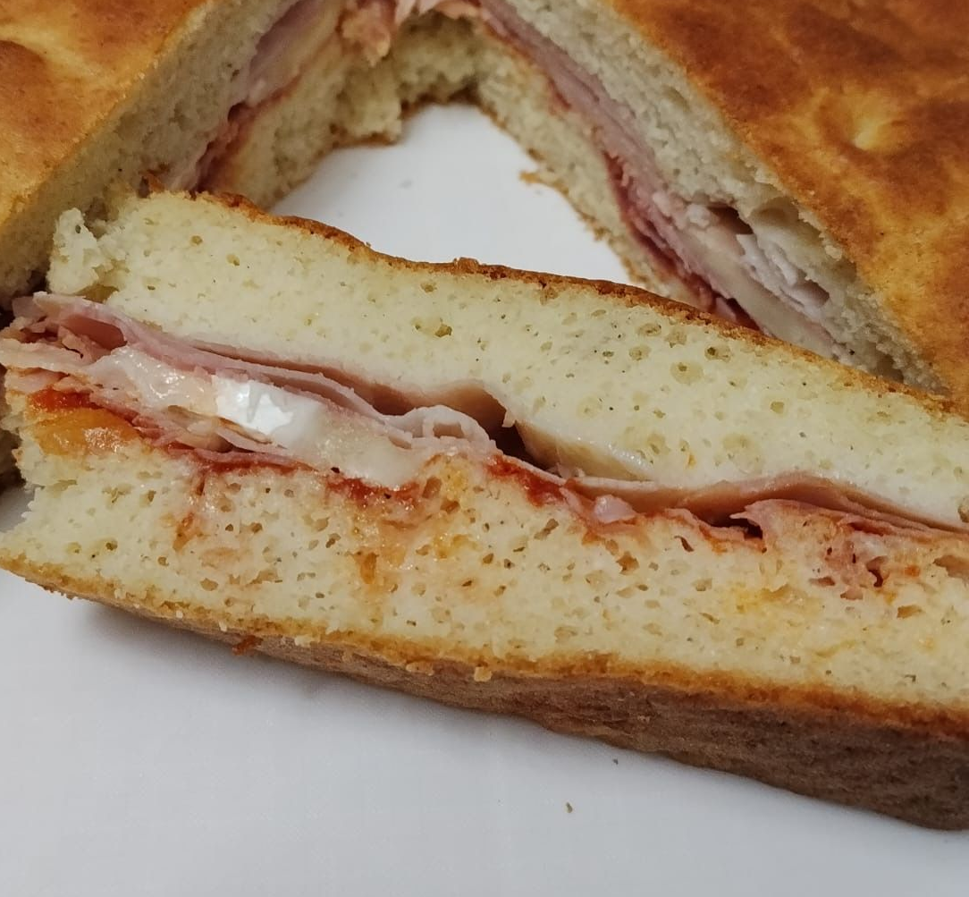 Primo piano di un toast con prosciutto e formaggio fuso su un piatto bianco