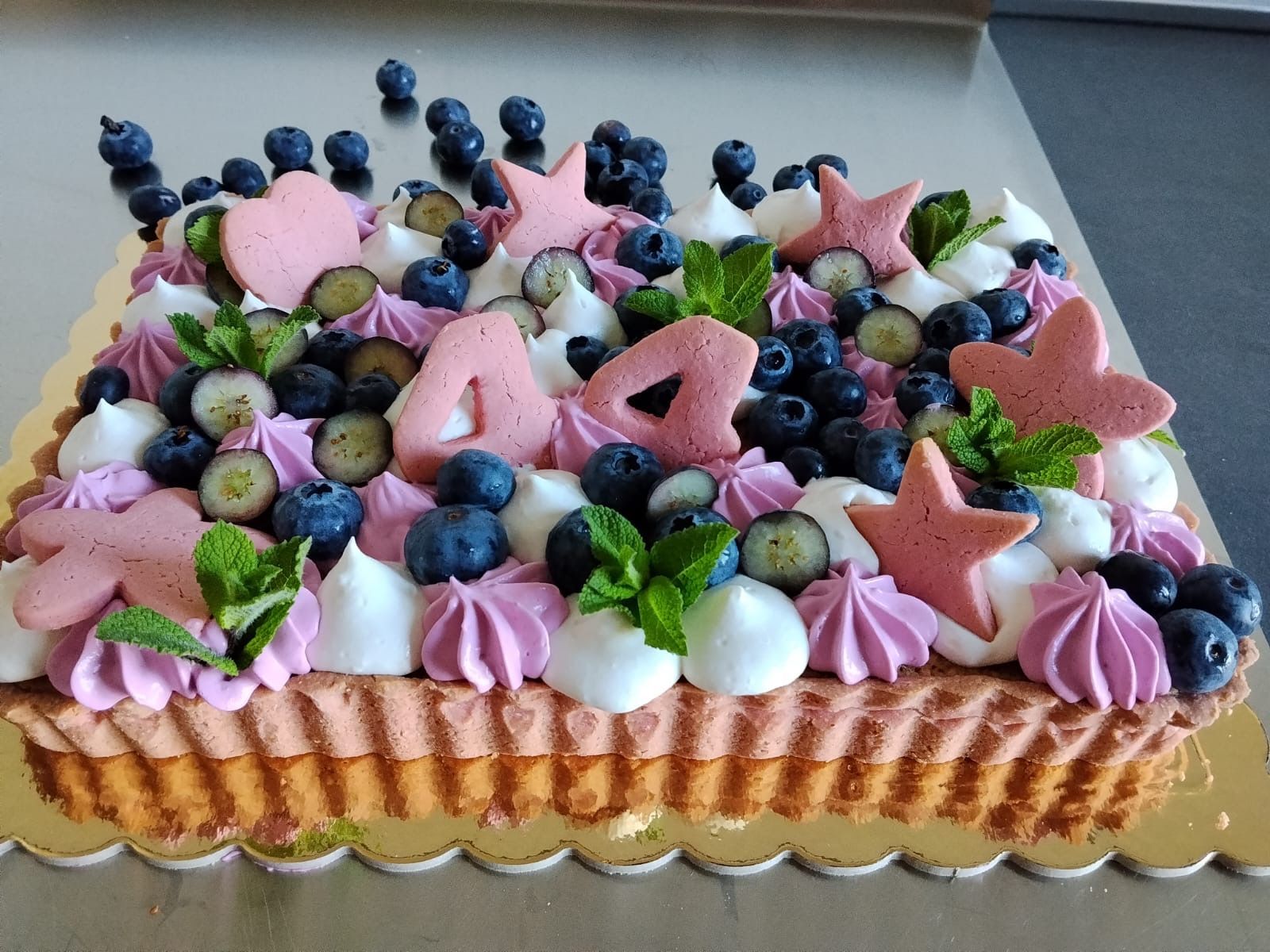 Torta alle fragole decorata con mirtilli, glassa rosa e pezzetti di frutta a forma di stella