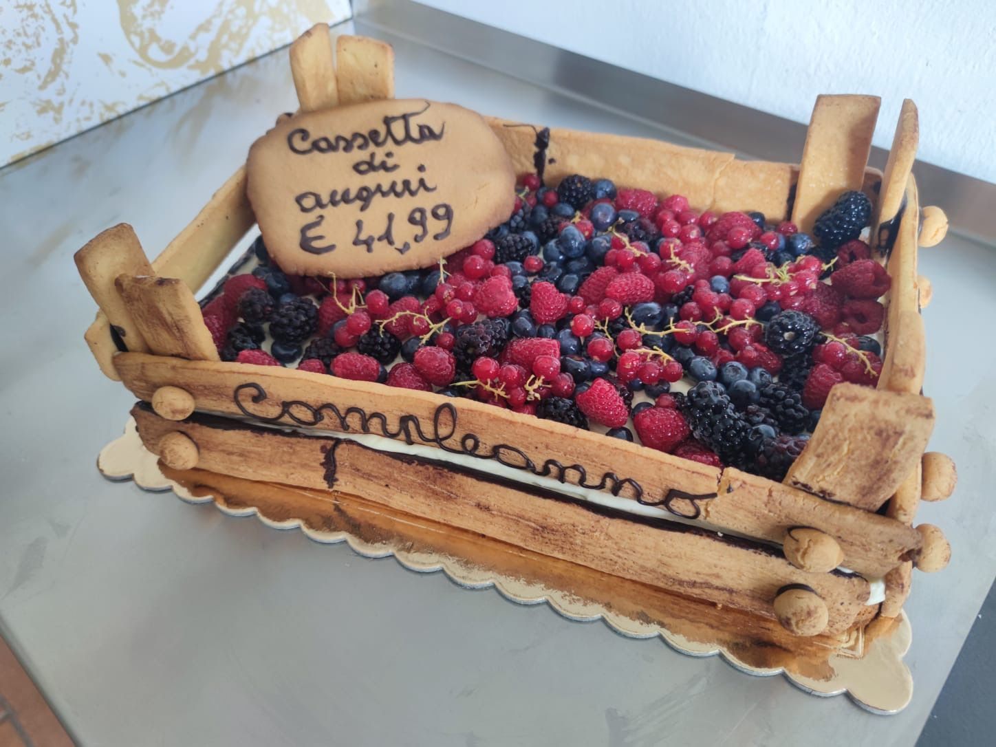 Cassetta rustica di legno con frutti di bosco misti e un cartello del prezzo con la scritta «Congolais quets? €1.99»