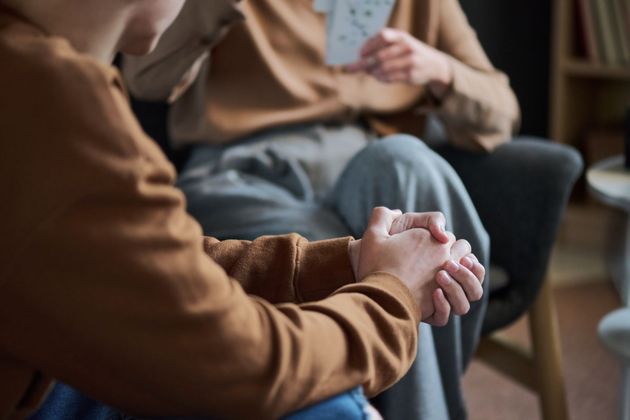 Two people seated close together, holding hands in a warm, softly lit room