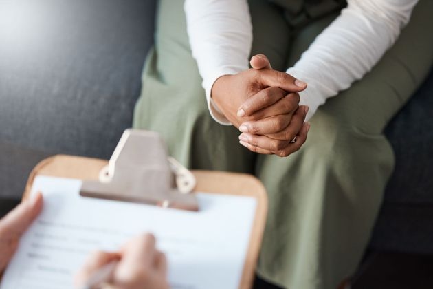 Therapist taking notes while a blurred client sits across from them in a counseling session
