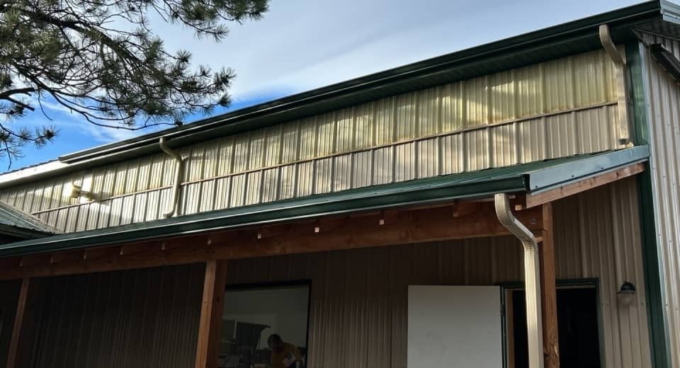 Wooden building exterior with slanted corrugated roof and green trim under a blue sky