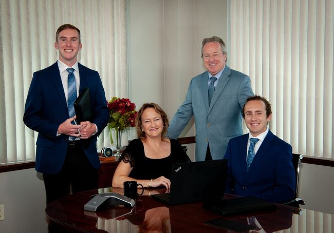A group of people in suits and ties are standing around a table.