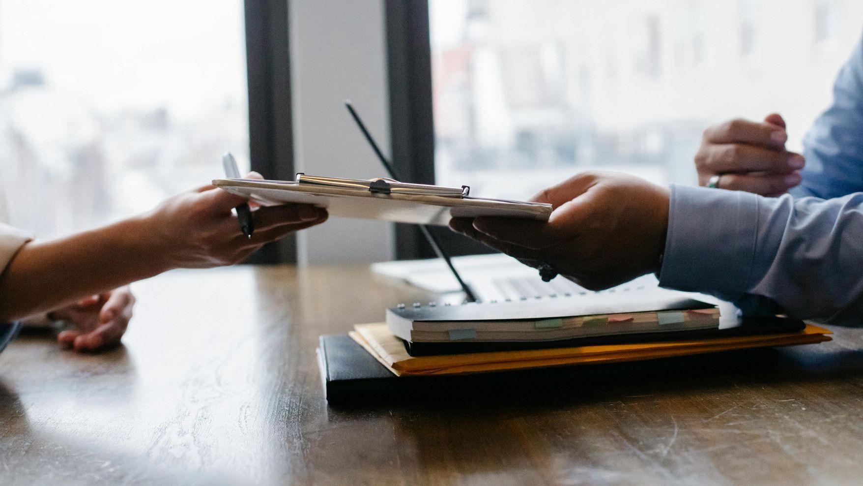 A man and a woman are sitting at a table holding a clipboard.