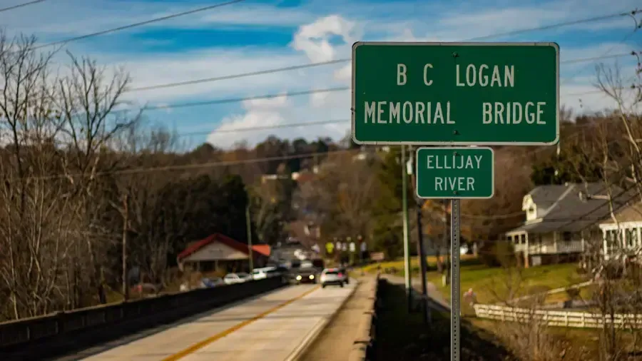 Road leading to B.C. Logan Memorial Bridge over the Cuyahoga River, with green highway signs.