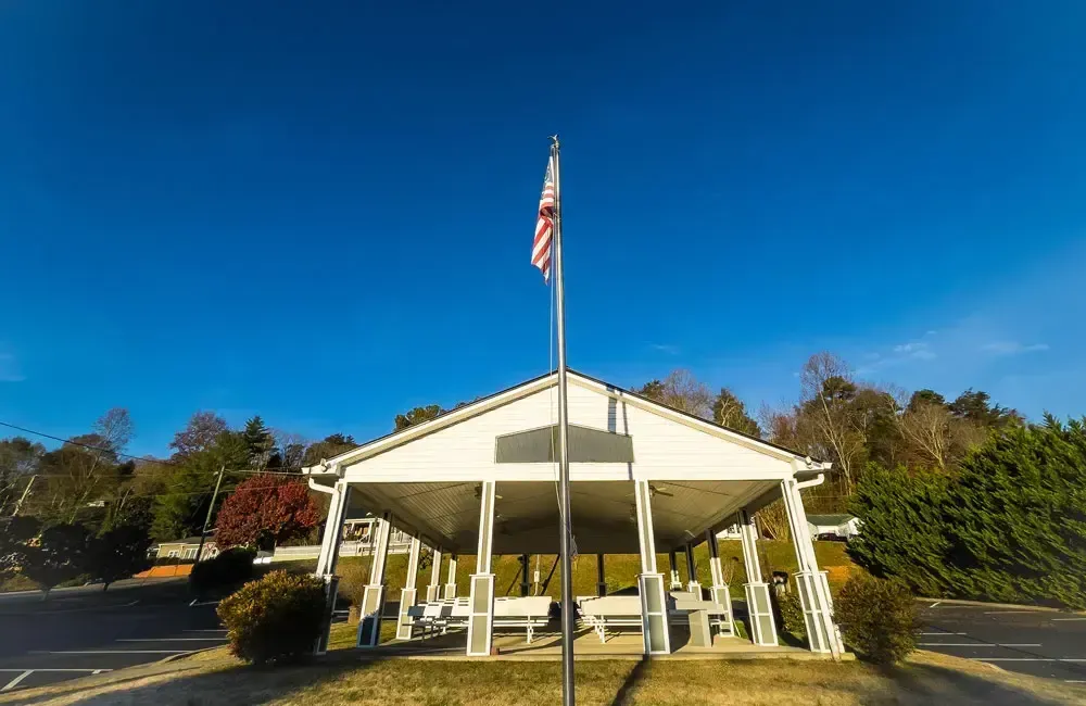 White building with columns and an American flag in front, under a clear blue sky
