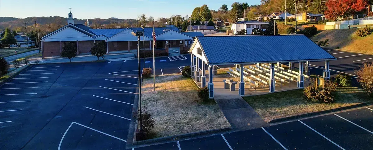 Aerial view of a church campus with a blue roof and parking lot at sunset