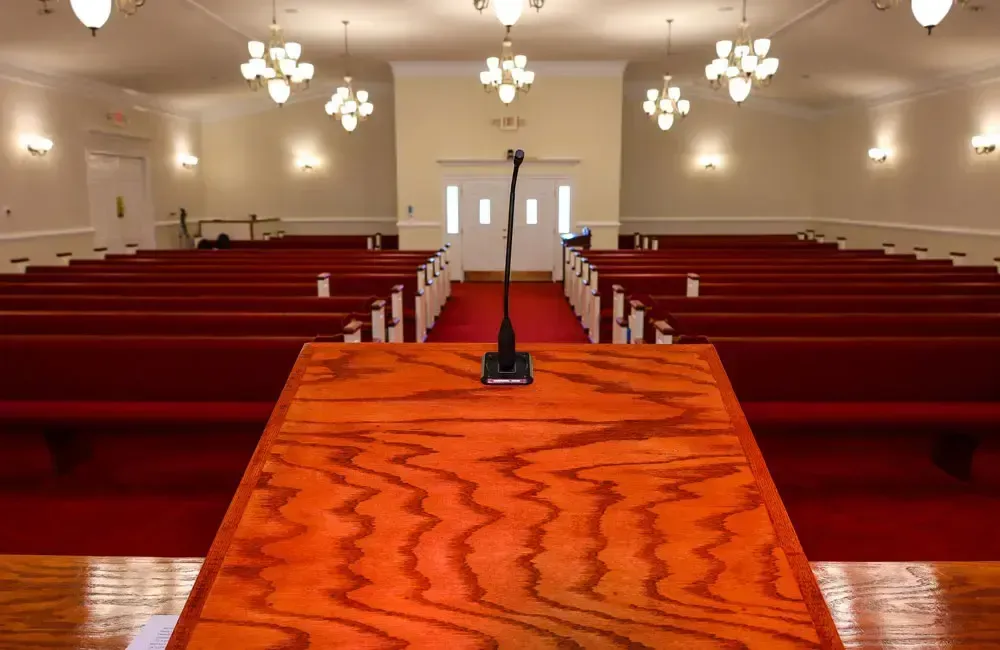 Church sanctuary with red pews and an orange carpeted aisle facing the pulpit