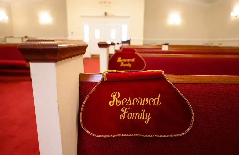 Red church pews with red “Reserved Family” signs in a bright sanctuary