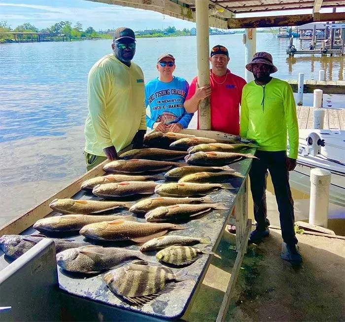 A group of men are standing around a table full of fish.