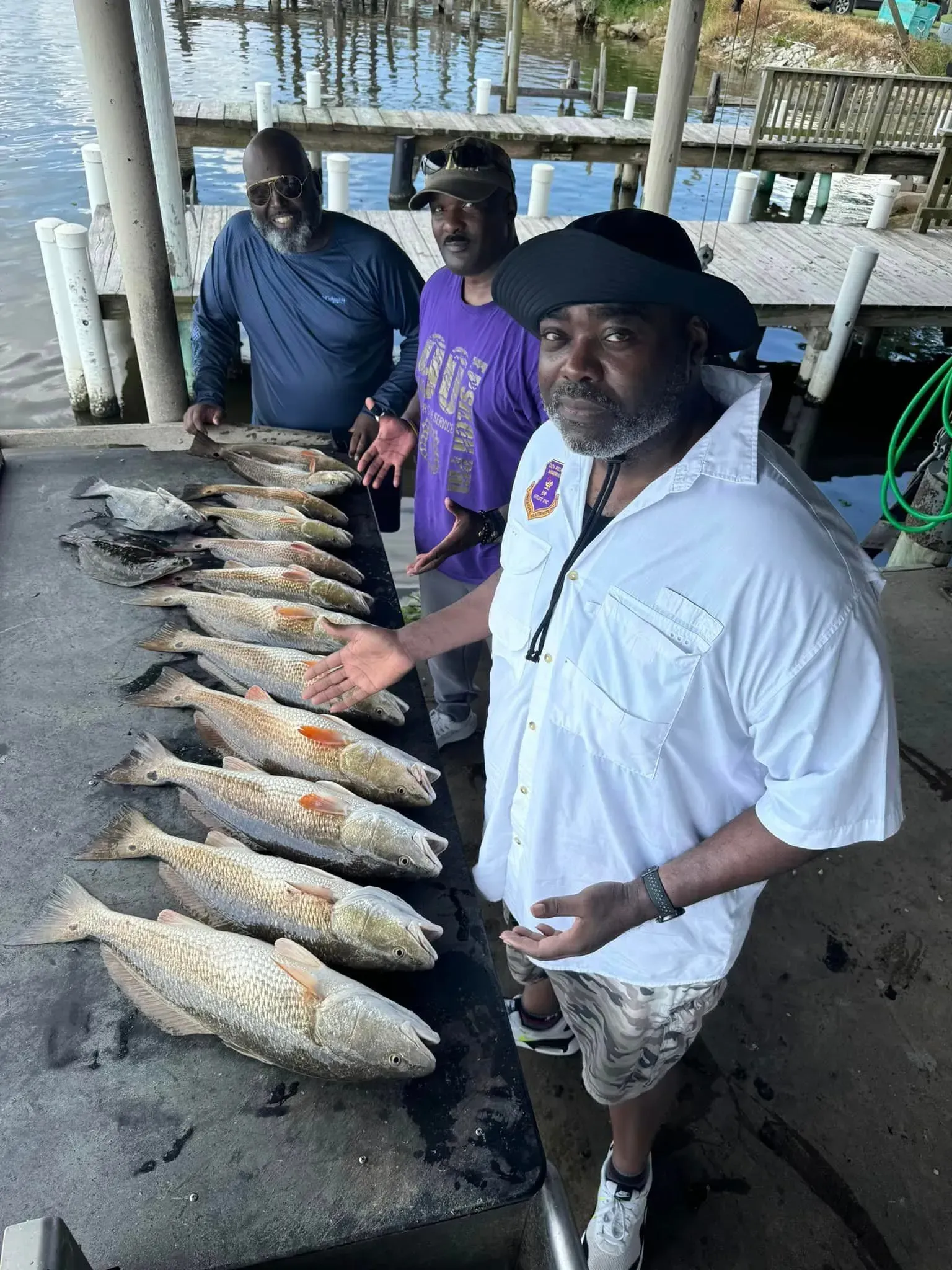 Three men are standing next to a table full of fish.