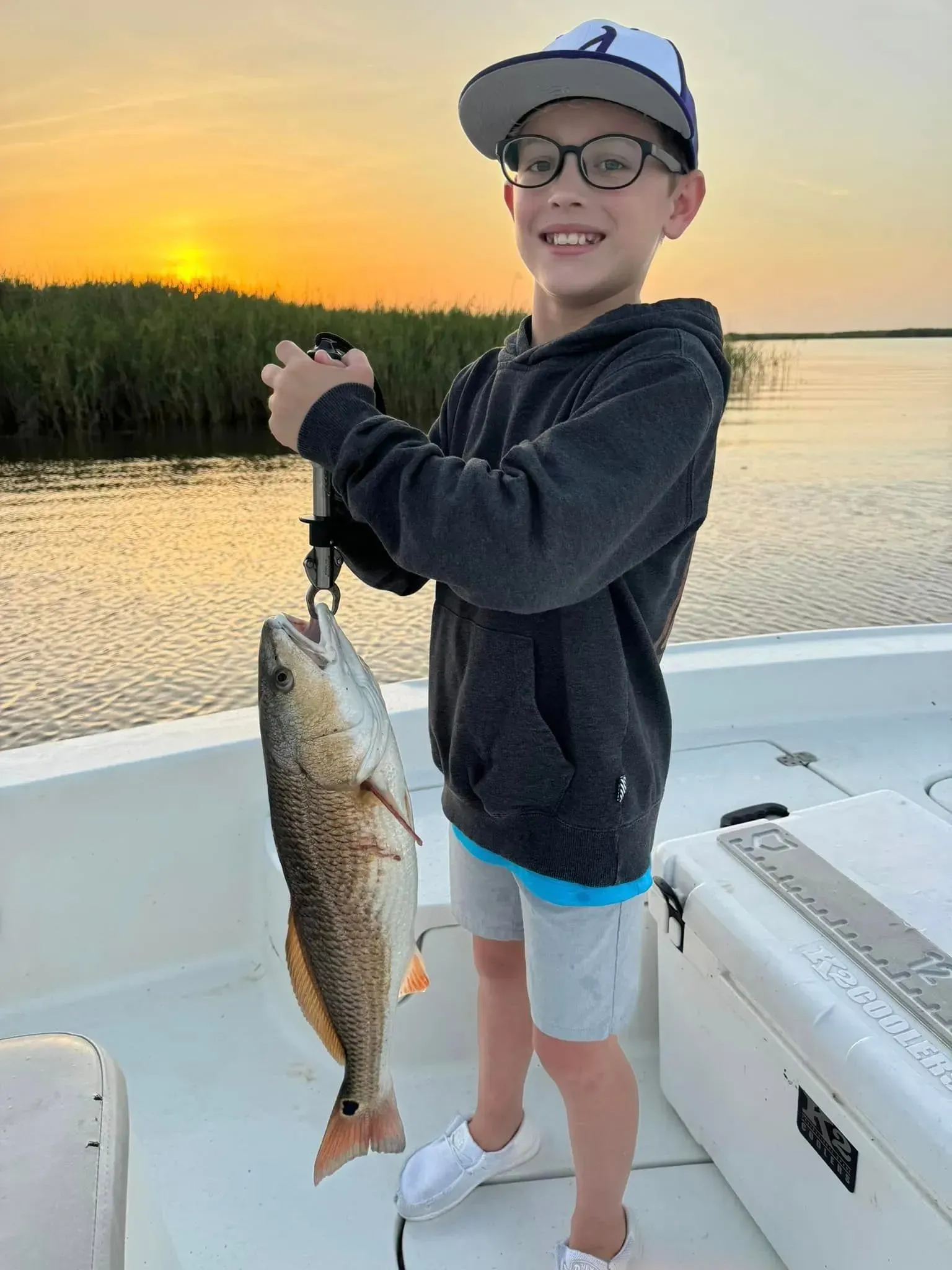 A young boy is holding a fish on a boat.