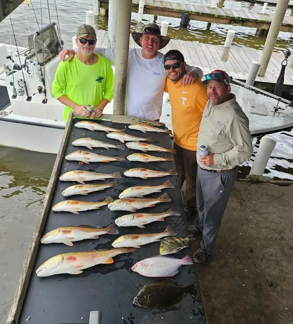 A group of men are standing around a table full of fish.
