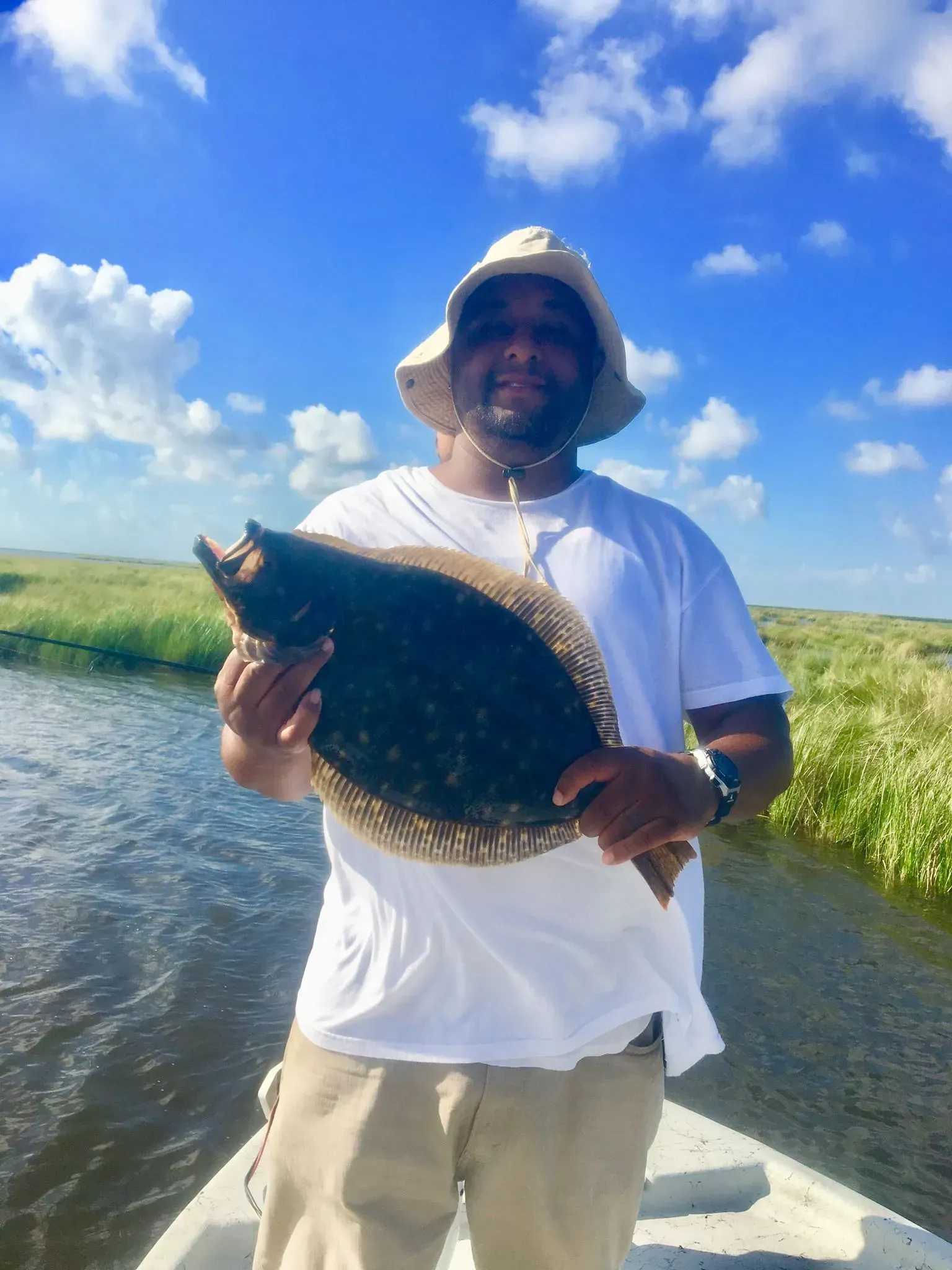 A man is standing on a boat holding a large fish.