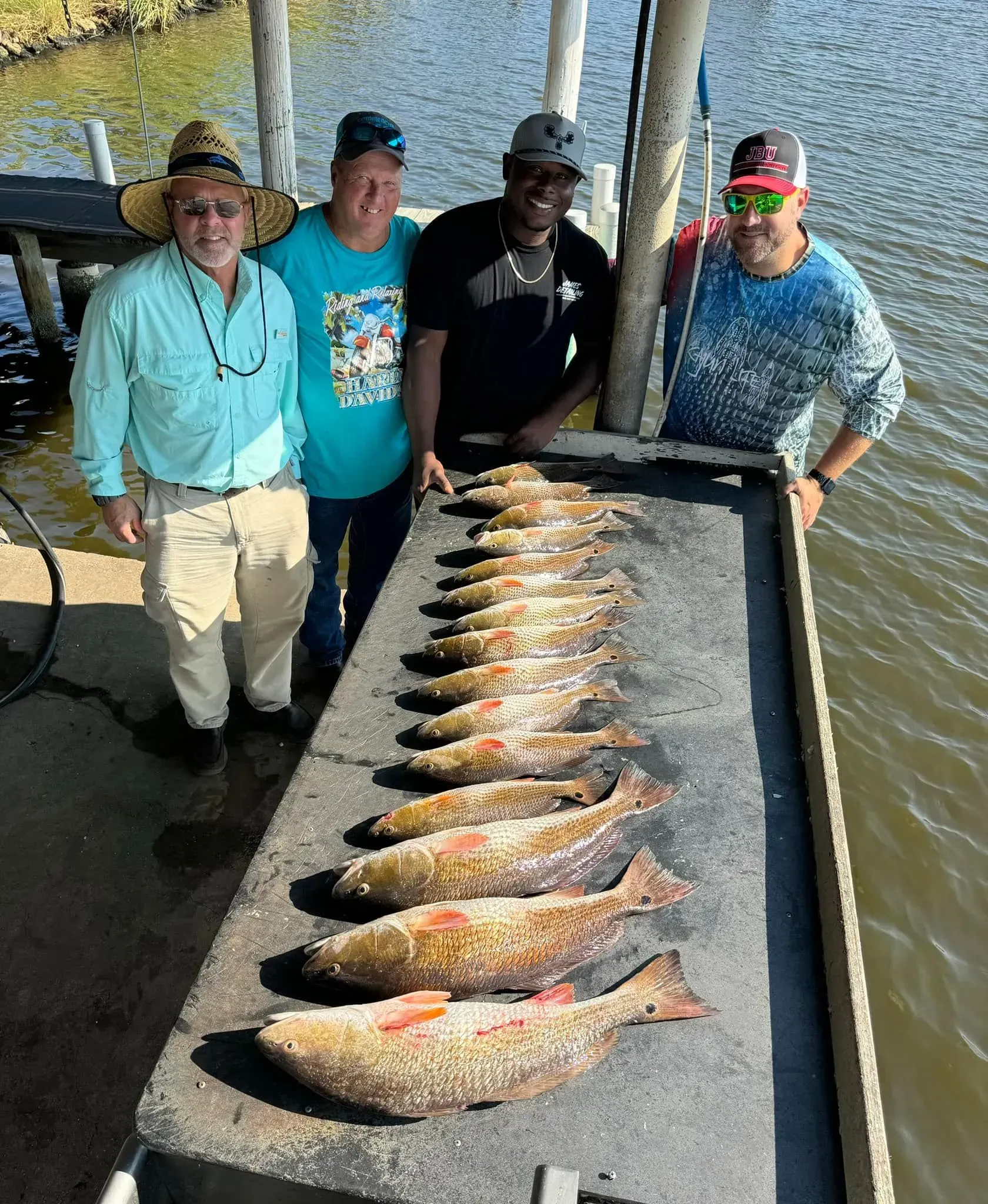A group of men are standing next to a table filled with fish.
