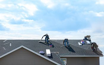 A group of men are working on the roof of a house.