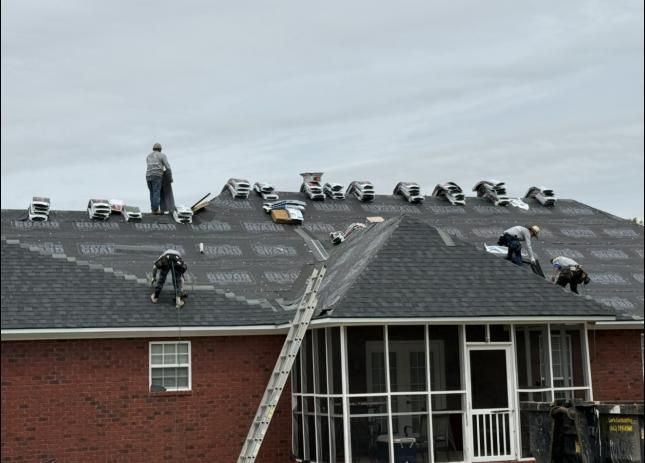 Roofers working on a brick house roof under cloudy skies