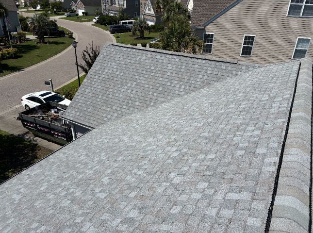 Roof shingles with a gutter; a pickup truck and suburban homes are visible below.