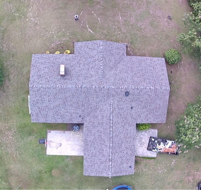 Aerial view of a house with a gray roof, small porch, and patchy grass yard
