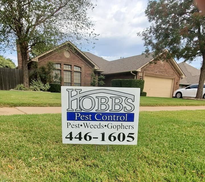 Sign for Hobbs Pest Control in front of a house.