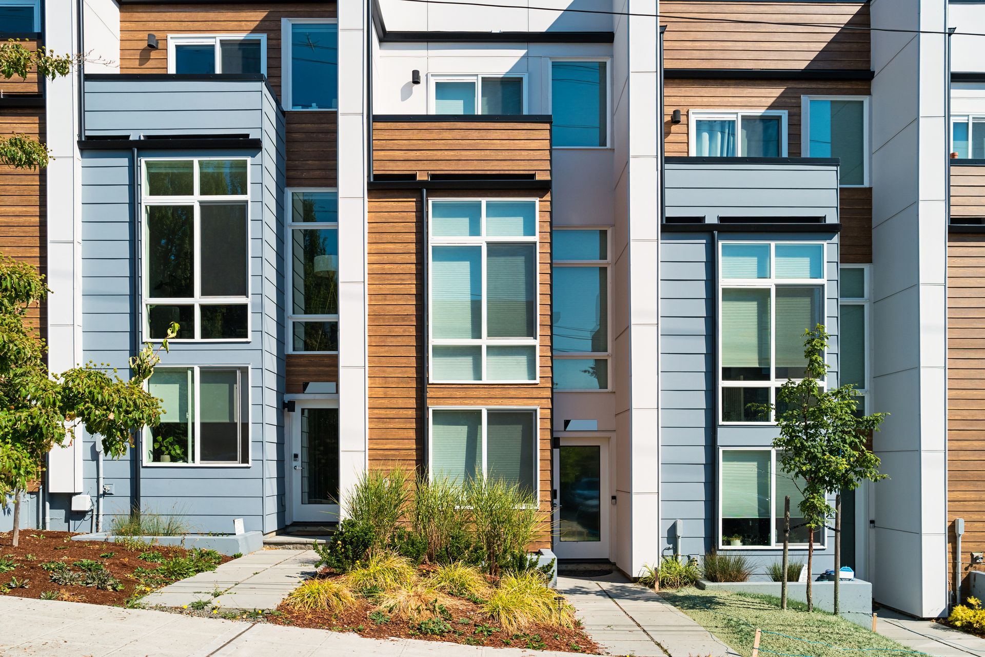 Row of modern townhomes with varying wood and blue siding.