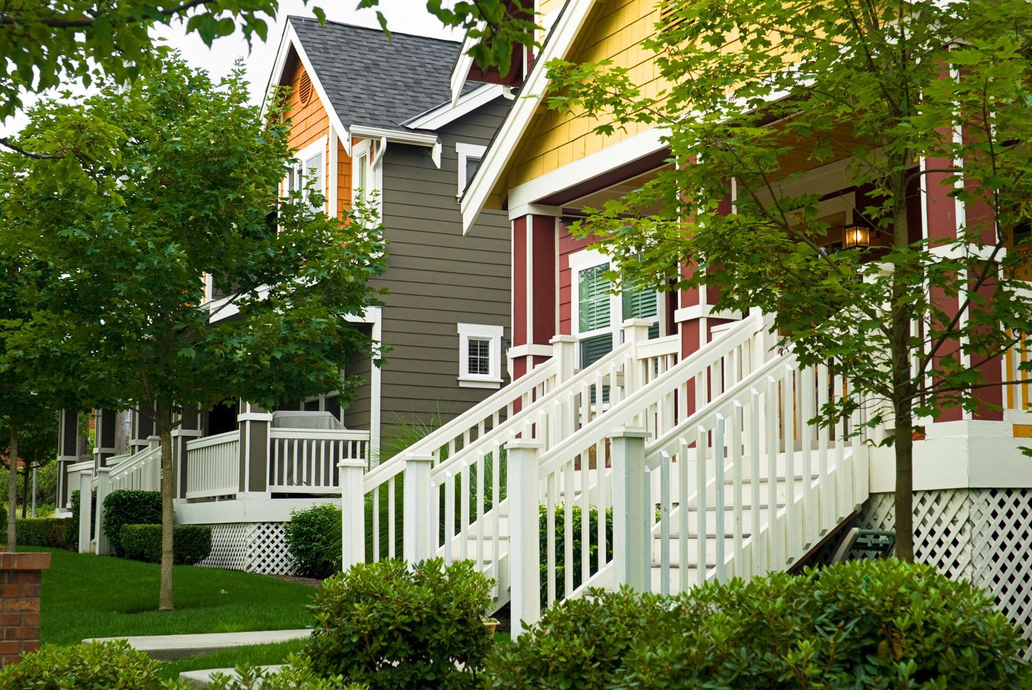 Colorful row houses with white railings and green lawns.