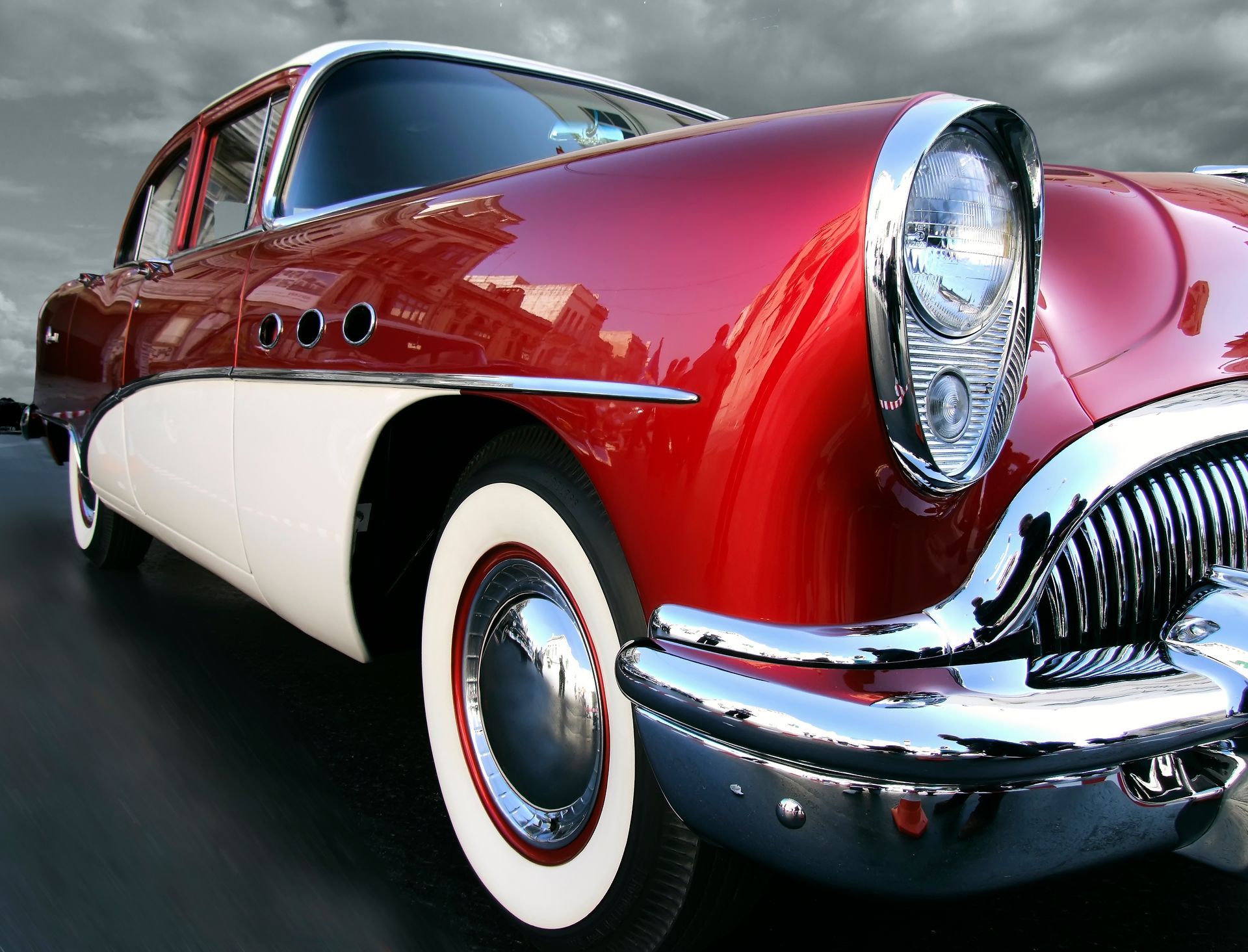 Red and white vintage car with chrome accents; tires have white walls.
