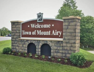 Welcome sign for Town of Mount Airy on a stone monument with arched cutouts and greenery
