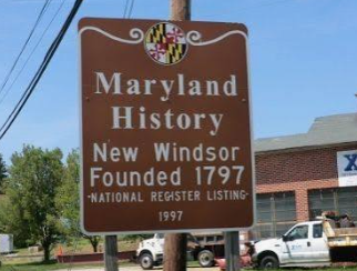 Brown Maryland Historic sign for New Windsor Foundry 1797 with National Register listing, outdoors by a road. Brown Maryland Historic sign for New Windsor Foundry 1797 with National Register listing, outdoors by a road.