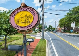 Reisterstown, Maryland town sign beside a sunny roadside with sidewalk and houses Reisterstown, Maryland town sign beside a sunny roadside with sidewalk and houses