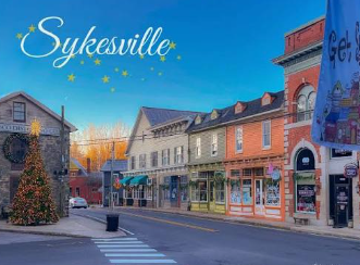 Sykesville main street with shops, a brick clock tower, and a decorated Christmas tree at dusk Sykesville main street with shops, a brick clock tower, and a decorated Christmas tree at dusk