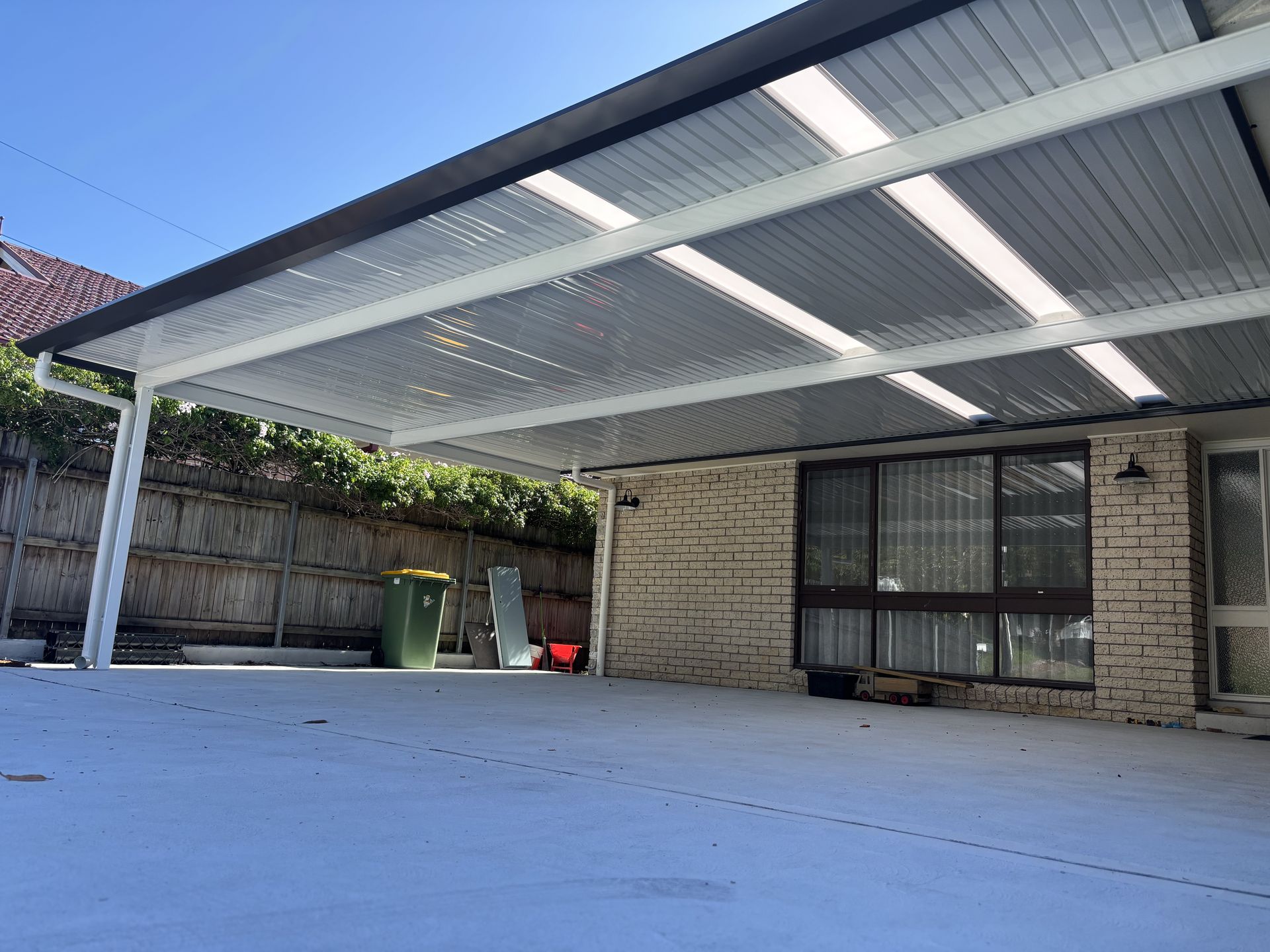A Black Roof With White Panelling Underneath Over an Outdoor Dining Area — Outdoor Leisure Living In Tuggerah, NSW