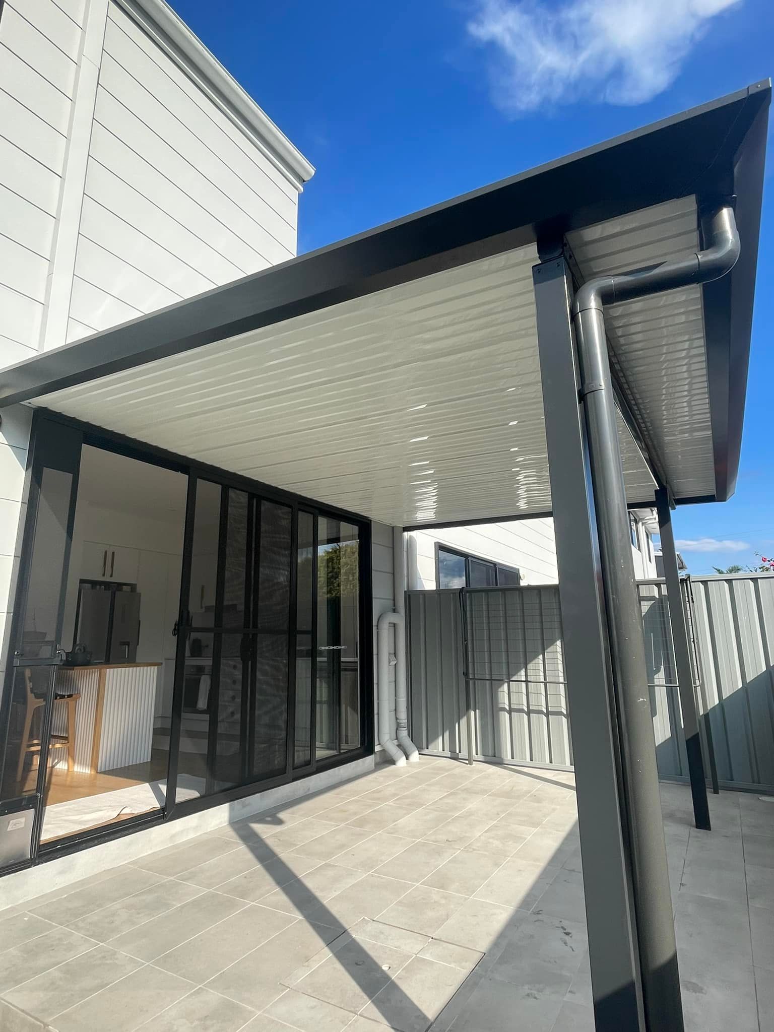 A Brick House With a Patio With Wicker Furniture and a Pergola In  The Central Coast