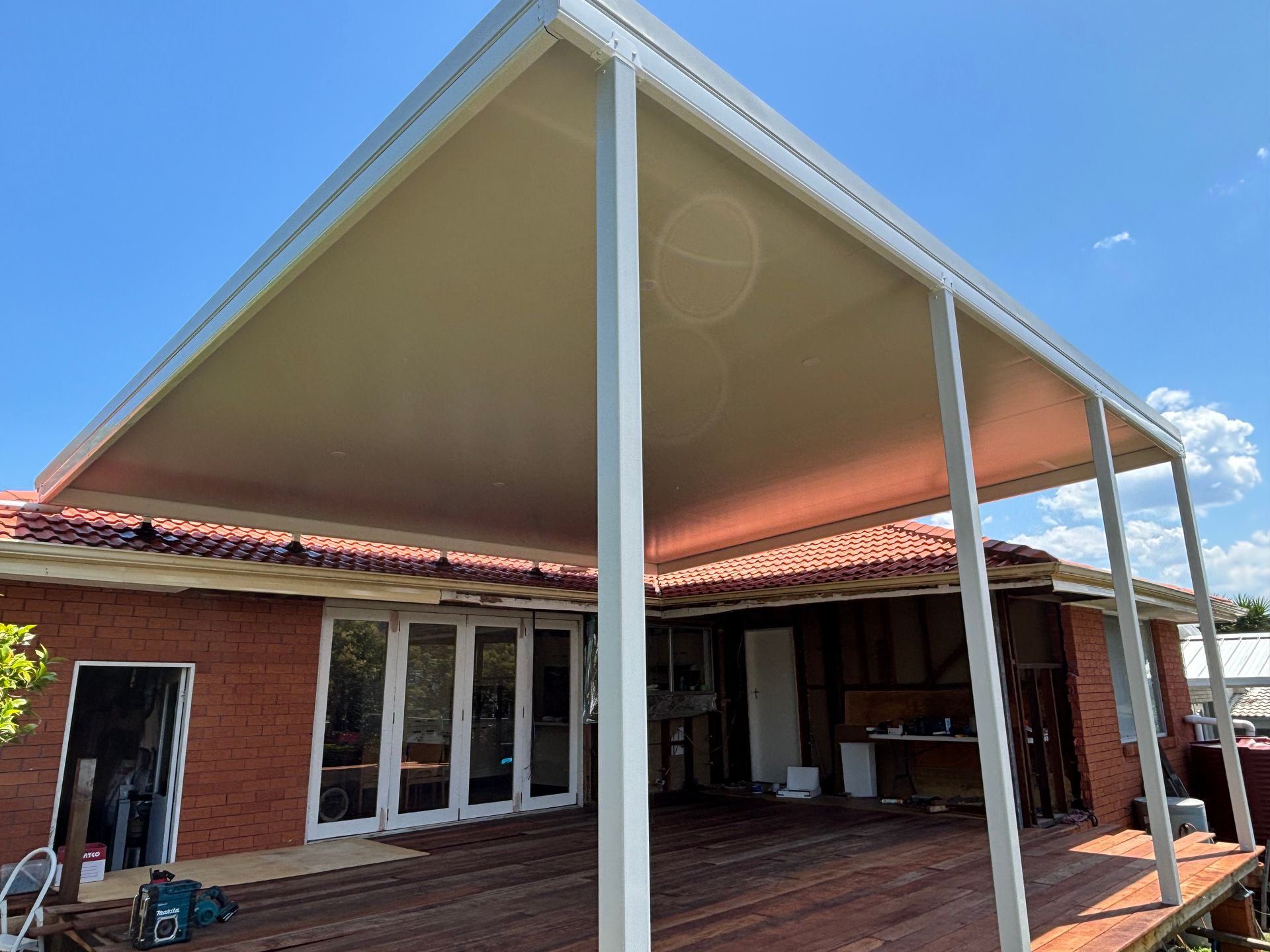 White Patio Cover Attached to a Brick House With a Wooden Deck —In The Central Coast
