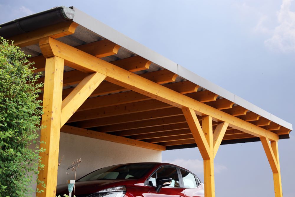 A Red Car is Parked Under a Wooden Carport — Outdoor Leisure Living In Woy Woy, NSW