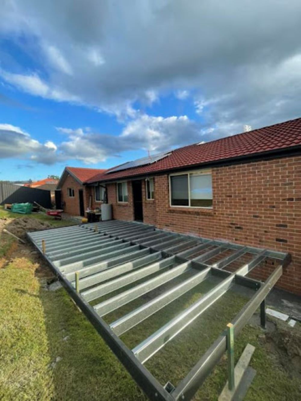 A Brick House With a Metal Deck in Front of It — Outdoor Leisure Living In Tuggerah, NSW