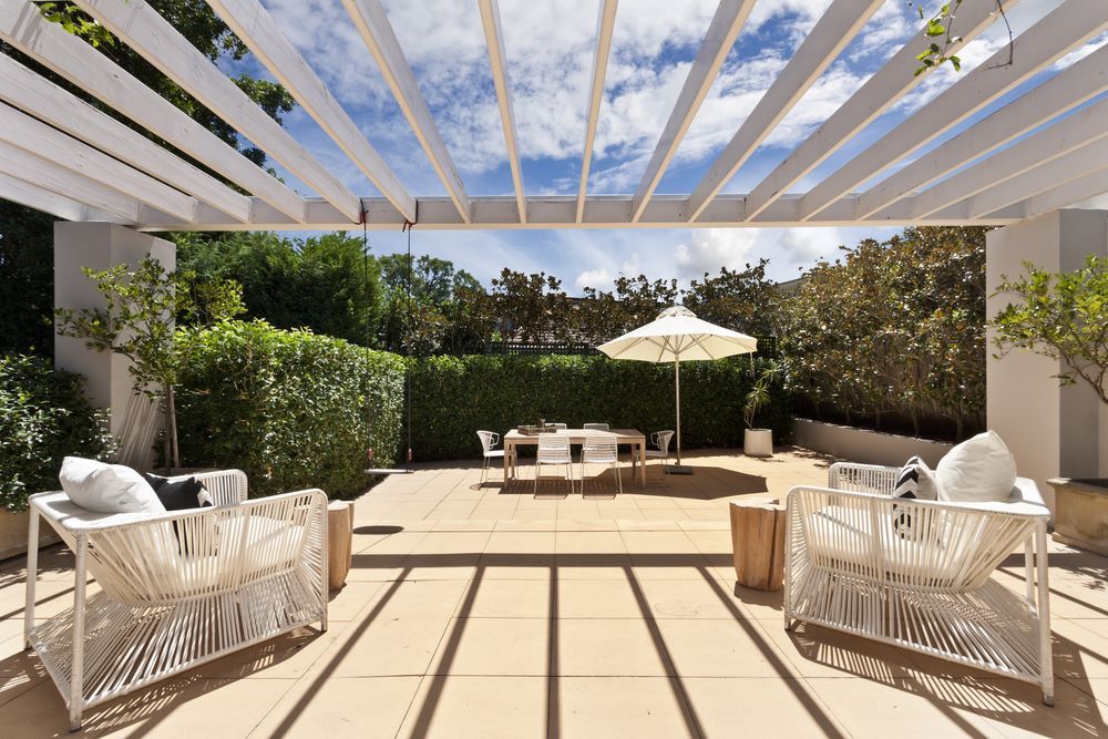 A Patio With Chairs and an Umbrella Under a Pergola — Outdoor Leisure Living In Gosford, NSW